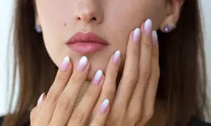 Delikatne baby boomer nails na dłoniach kobiety, z subtelnym ombre od różu do bieli.