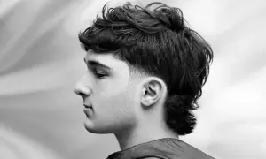 Czarno-białe zdjęcie mężczyzny z nowoczesną fryzurą typu mullet, widok z profilu.