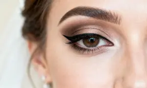 Oko z perfekcyjnym makijażem glamour: brązowe cienie, kreska typu kocia i wytuszowane rzęsy.