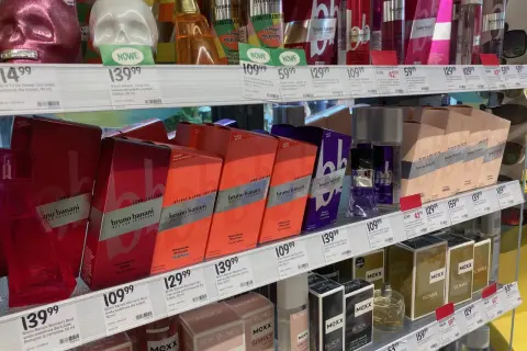 Półki z perfumami w drogerii, w tym flakony w kształcie czaszek i pudełka z marką Bruno Banani.