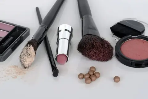 Zestaw do makijażu krok po kroku: puder, szminka, róże i pędzle.