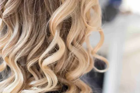 Falujące, blond włosy z subtelnymi, ciemnymi pasemkami, tworzącymi naturalny efekt.