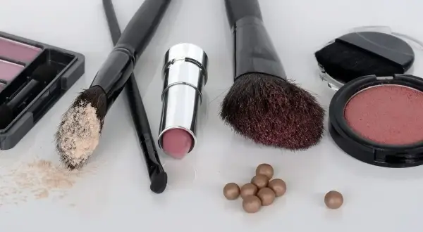 Zestaw do makijażu krok po kroku: puder, szminka, róże i pędzle.
