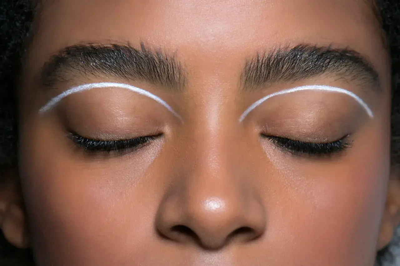 Oczy z makijażem w stylu cut crease, podkreślone białymi liniami nad powiekami.