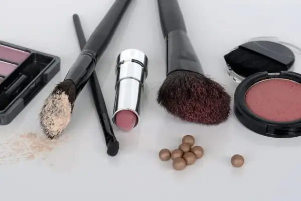 Zestaw do makijażu krok po kroku: puder, szminka, róże i pędzle.
