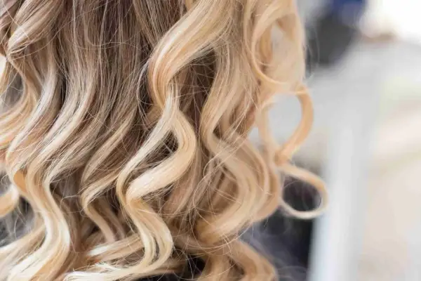Falujące, blond włosy z subtelnymi, ciemnymi pasemkami, tworzącymi naturalny efekt.